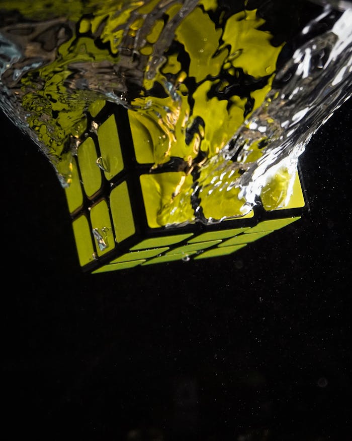 A Rubik's Cube captured in a dynamic splash underwater with striking lighting.